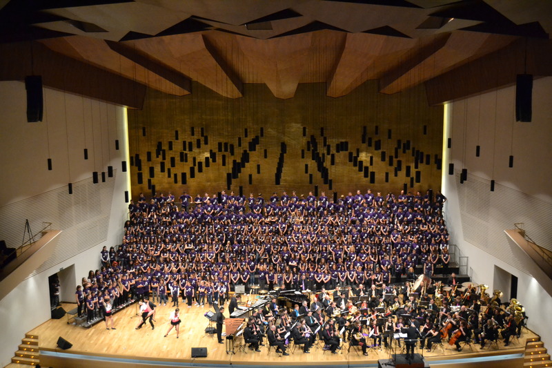 A photo of the choir and orchestra onstage during a Batucada performance.