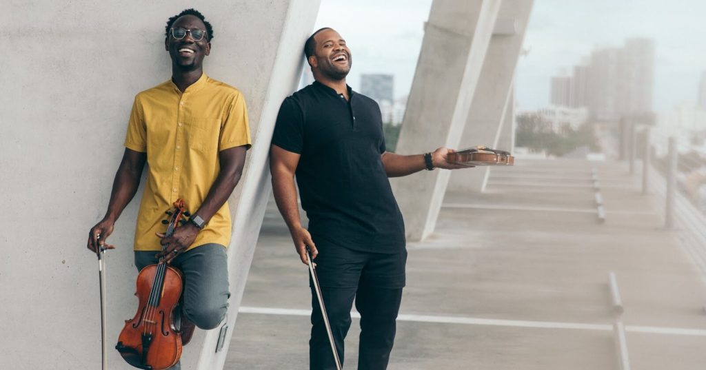 A promotional photo of Kevin Marcus and Wilner Baptiste of the music duo Black Violin.