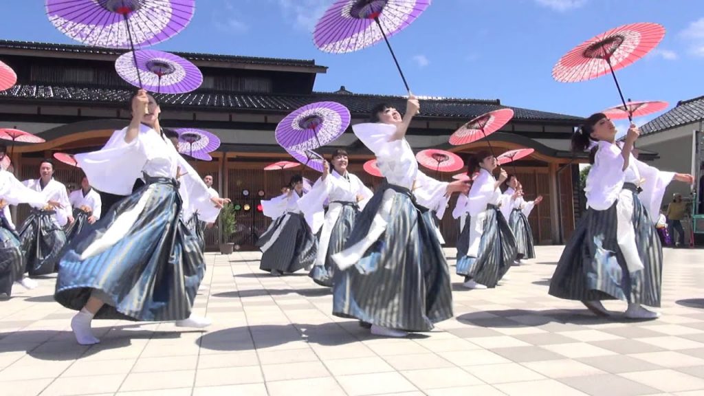 A photo of the Maigen dancers mid-performance, their umbrellas held up in the air.