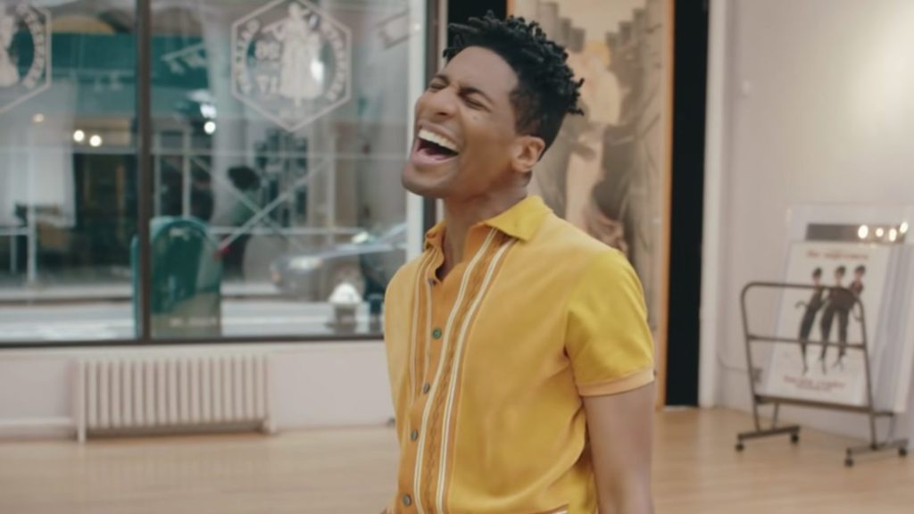 A photo still of Jon Batiste singing from the music video for I Need You.