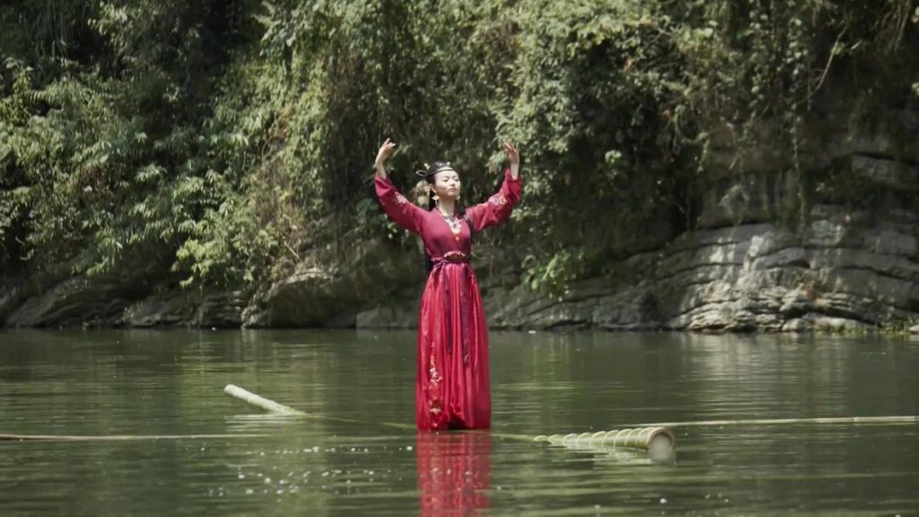 A photo of a Chinese dancer performing the art of single bamboo pole rafting.