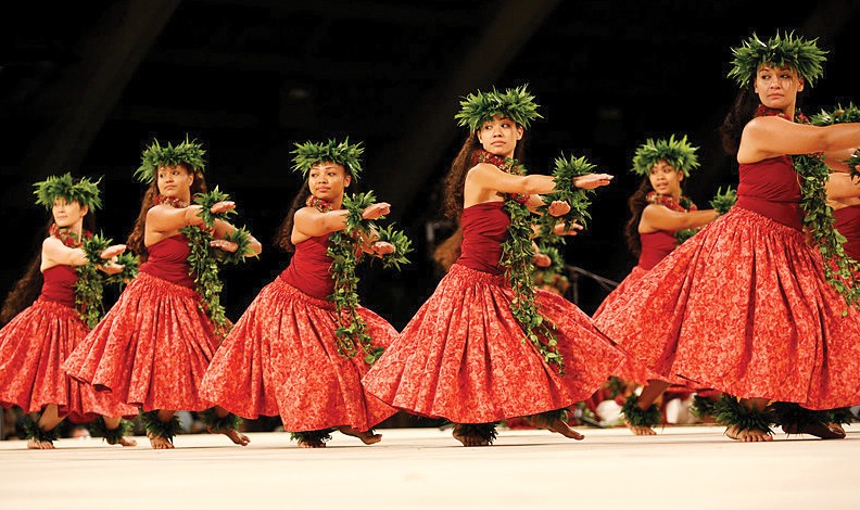 A photo of female hula dancers of the Wahine Kahiko division, mid-performance at the Merrie Monarch Festival.