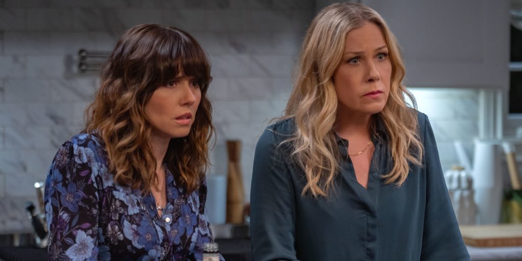 A photo still from an episode of Dead to Me. Lead actors Christina Applegate and Linda Cardellini are in a kitchen, staring intensely at someone out of frame.