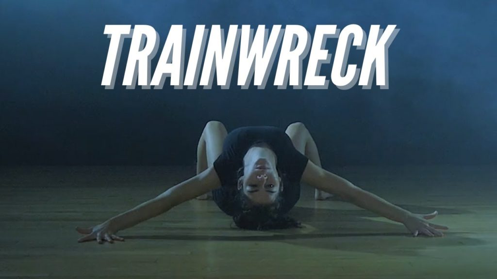 A photo of dancer Megan Miller, on her back, arms outstretched, head titled back and staring straight at the camera. The word Trainwreck is superimposed above her.