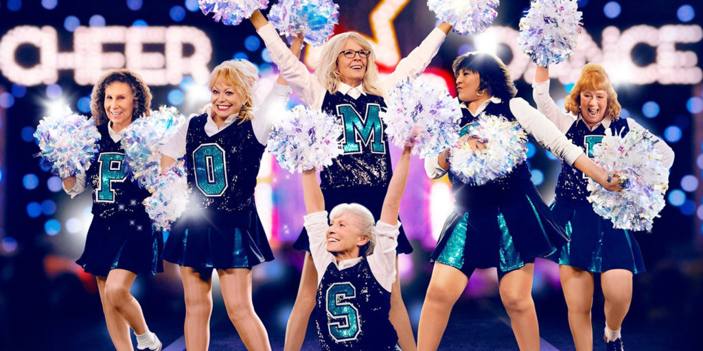 A promotional photo of the cast of Moms, wearing their cheerleading outfits, mid-cheer with pom poms in the air.