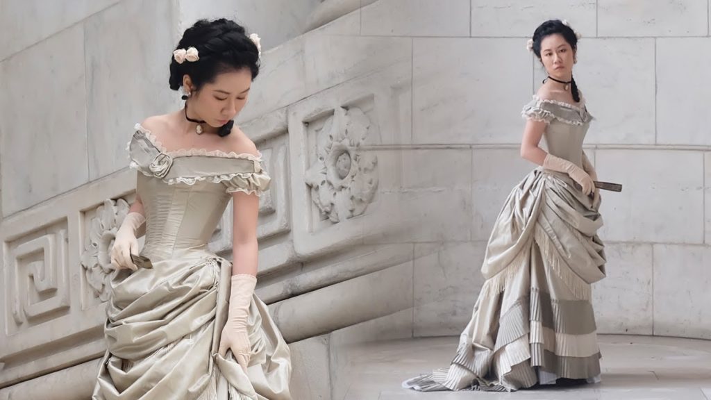 Two side by side photos of Claire Zhang wearing an off-white and grey coloured Victorian bustle gown.