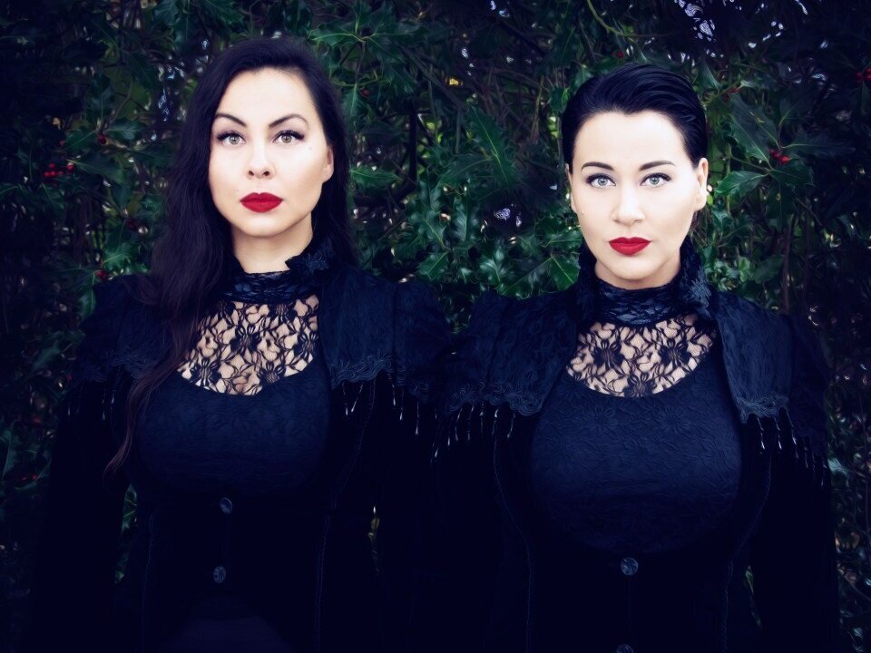 A promotional photo of Inuksuk Mackay and Tiffany Ayalik of the musical duo PIQSIQ. They are standing side by side and staring straight into the camera.