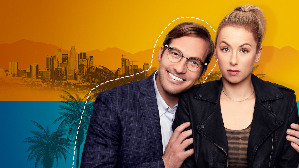 A promotional photo from the film Good on Paper. Lead actor Ryan Hanson is smiling directly into the camera with his arms around lead actress Iliza Shlesinger, who is looking directly into the camera with a perplexed expression on her face.