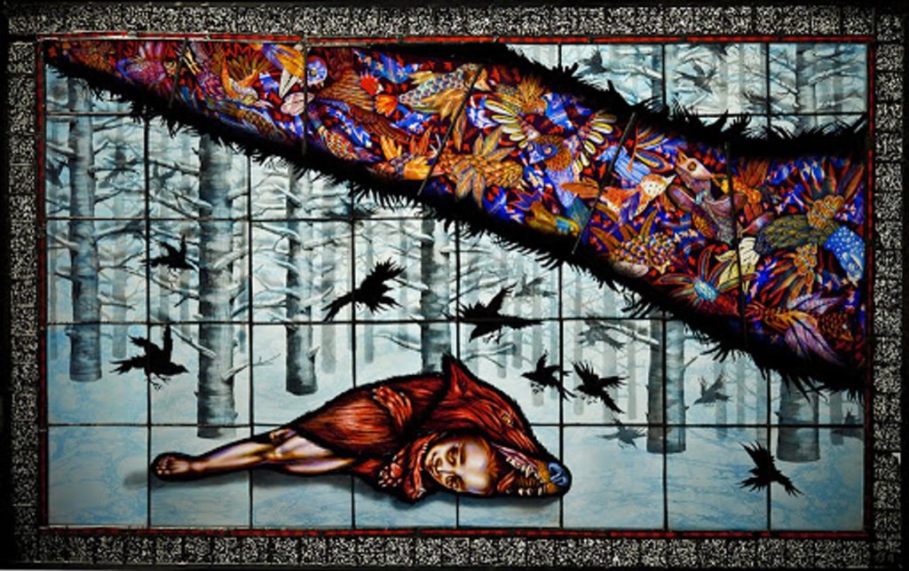 A image of a stained glass artwork by Judith Schaechter. The image shows a figure lying on the ground in a snow-covered forest with crows circling overhead.
