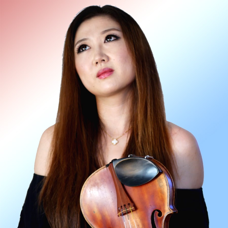 A close up photo of Michelle Jin, holding a violin to her chest and looking up.