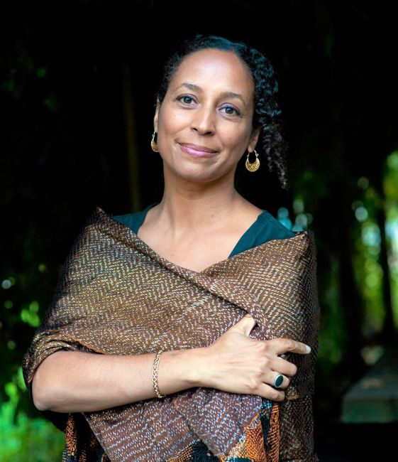 A close up photo of Danusha Laméris. She is crossing her arms and smiling straight into the camera.