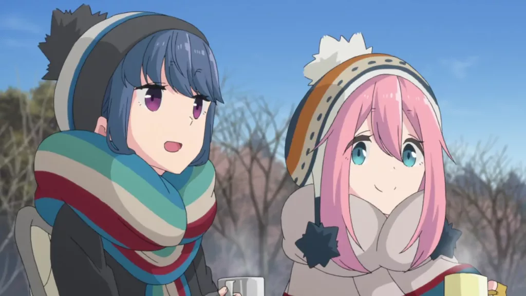 An animation still from the tv series Laid-Back Camp. Rin Shima and Nadeshiko Kagamihara are camping, sitting outdoors, wearing winter clothing and drinking tea.