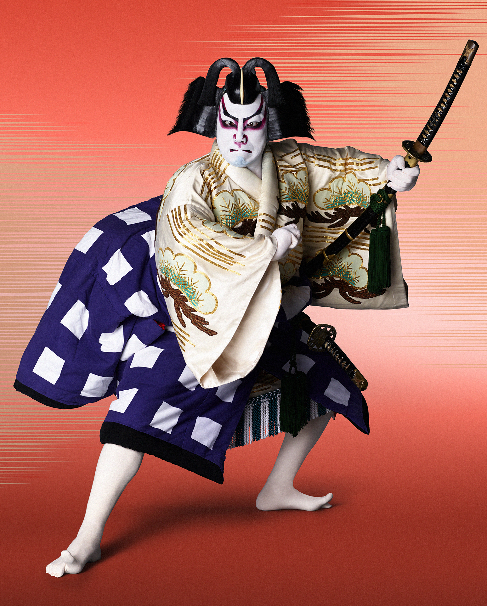 A photo of a kabuki theatre performer. He is dressed in a traditional costume against a red backdrop, adopting a dramatic pose, and holding a sword.