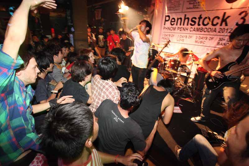 A photo of THE ANTI-fate performing at a bar in Phnom Penh. The audience is visible at the front of the stage.