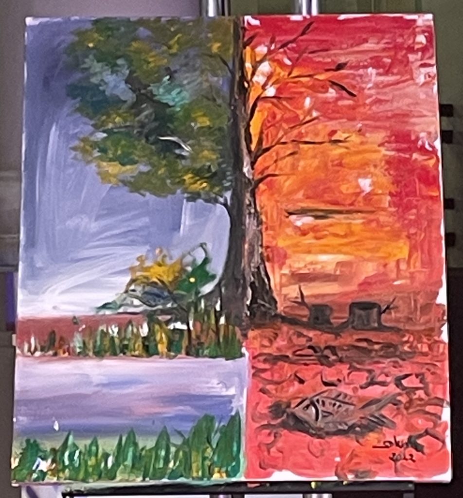 A close up photo of a painting by an artist with Phare Circus. It shows a tree in the middle of the canvas. On one side the tree is blooming with a blue background. On the other side the tree is bare with a red background.