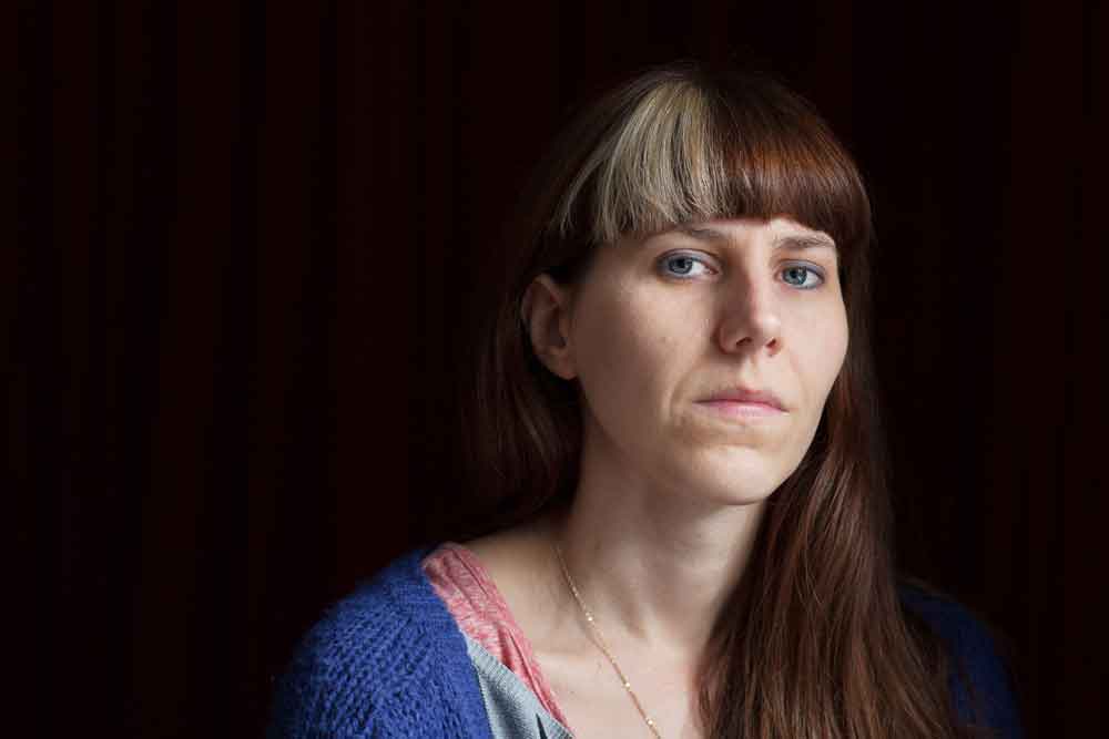 A profile photo of Emily Berry looking straight into the camera with a completely black background.