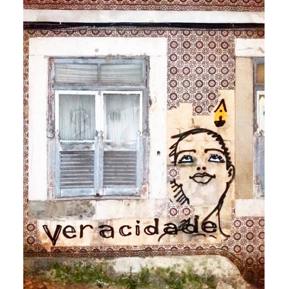 A photo of street art by Mauro Neri. The image is of a person looking up, their head next to a window, with the word "Veracidade" written underneath.
