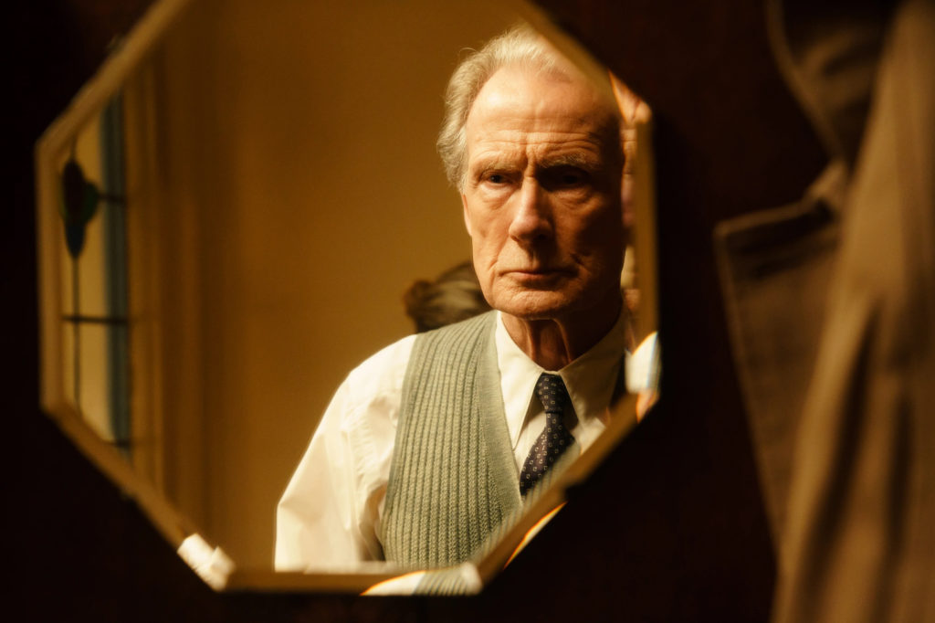 A photo still from the film Living. It shows lead actor Bill Nighy staring reflectively into a mirror.