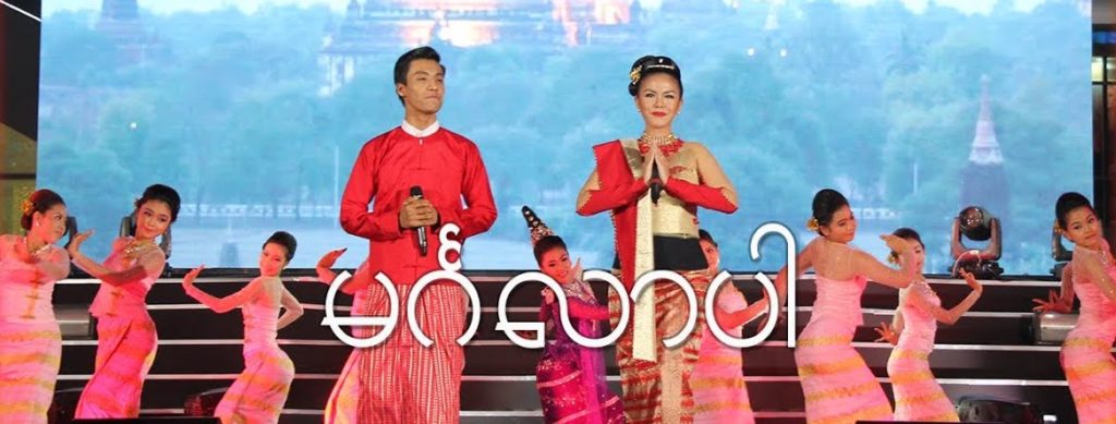 A photo of Aung Htet Ni Ni Khin Zaw on-stage, mid performance. There is a line of backup dancers behind them.