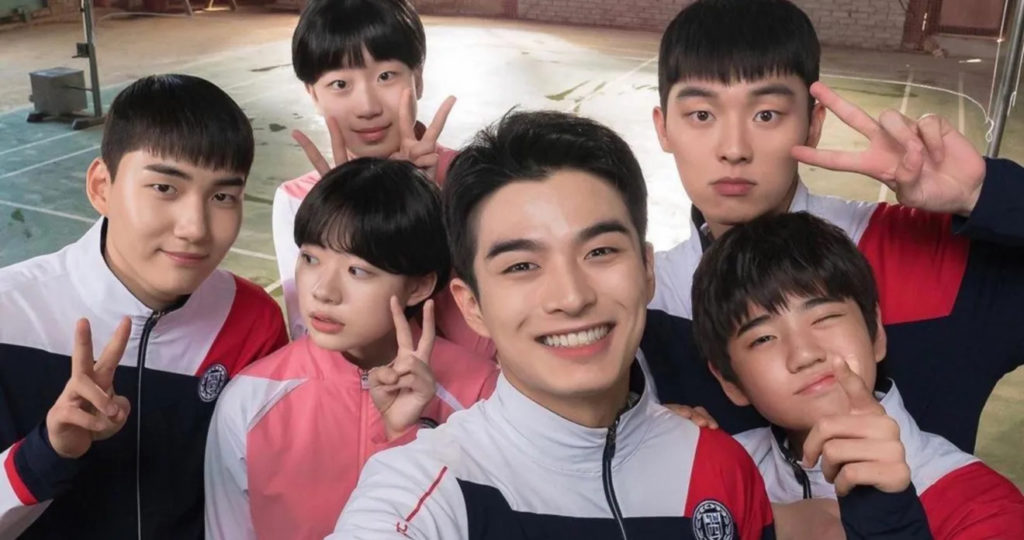 A promotional still from Racket Boys. It shows the young cast looking straight into the camera, as if taking a selfie, all smiling and holding up peace signs.