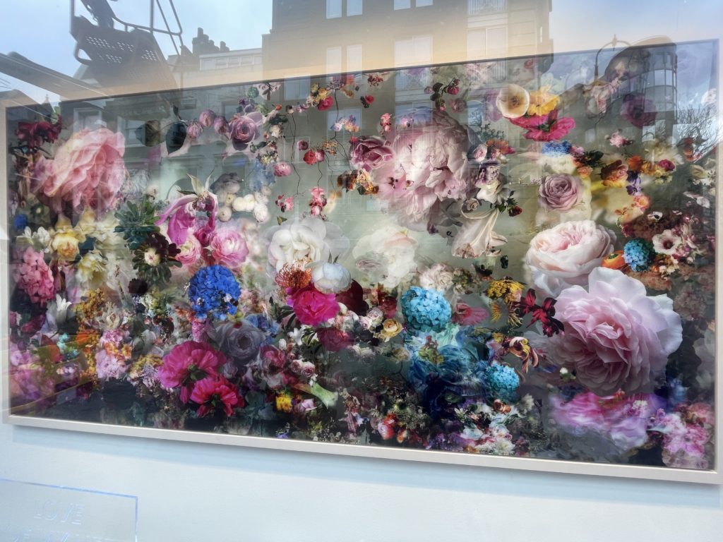 A photo of the painting La Vie En Rose by Isabelle Menin. It's a large landscape painting of hundreds of bright flowers.