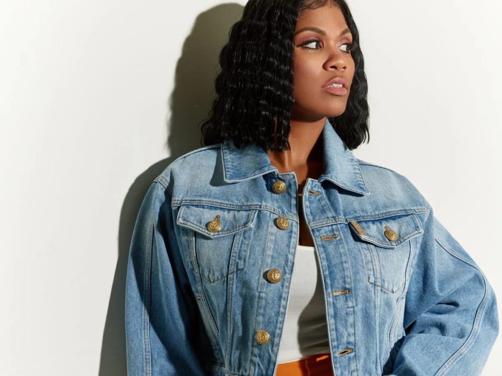 A photo of Candace Nicholas-Lippman. She is standing, posed, against a white wall and looking off to the right.