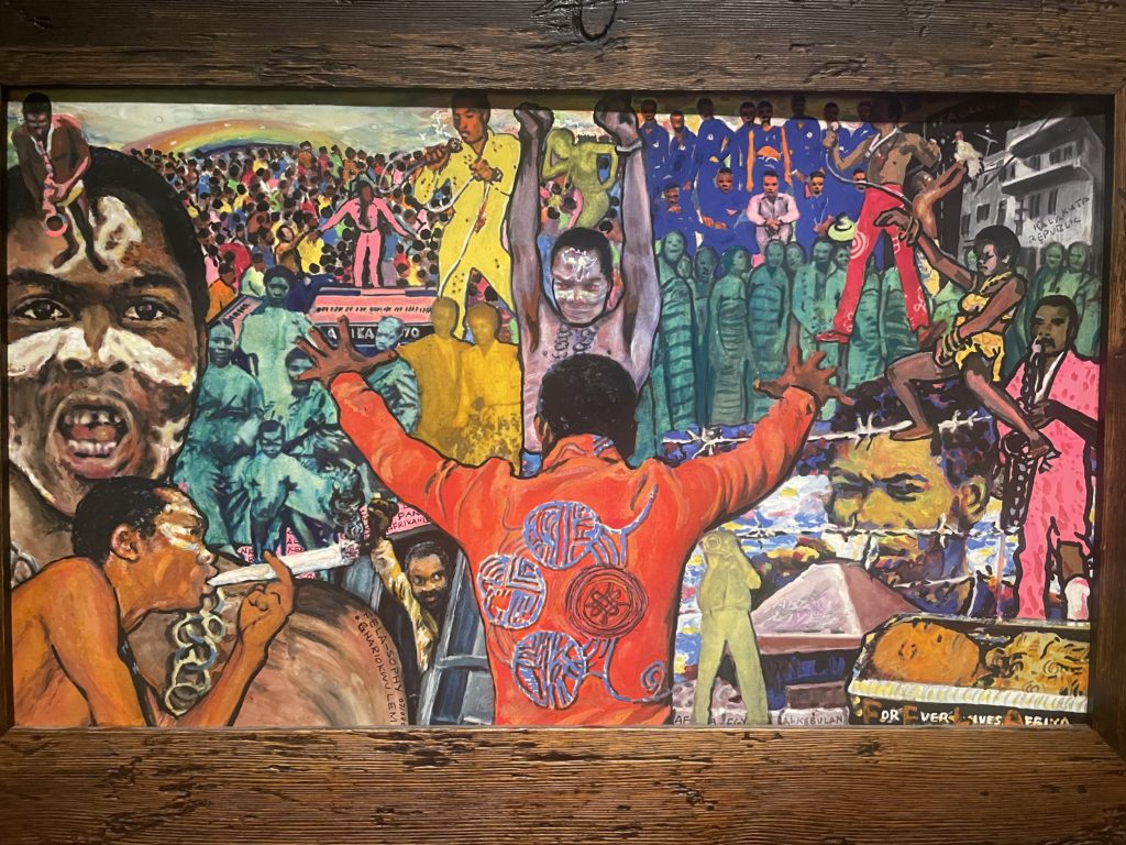 A photo of a painting by Lemi Ghariokwu. It is a collage of images of Fela Kuti throughout his life, all done in vibrant colours.