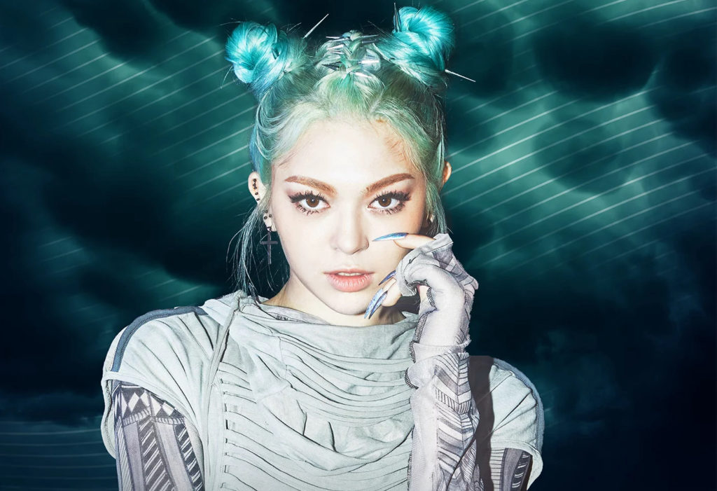 A promotional photo of AleXa. She is styled in silver and turquoise, her hair in bun pigtails, and she is staring directly into the camera.