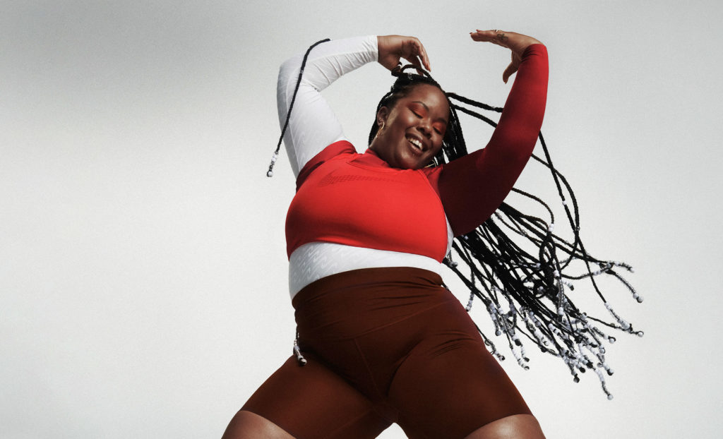 A photo of Trina Nicole. She is dancing, hands up in the air, a joyous smile on her face.