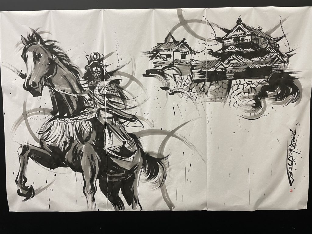 A photo of an ink painting of Matsuyama castle in the background, with a samurai on horseback in the foreground. The painting is black and white.