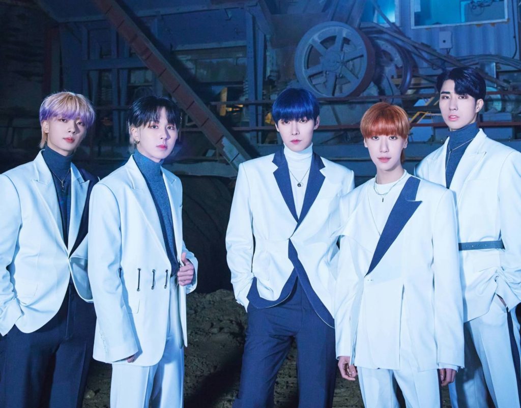 A promotional photo of ONEWE. The five members are wearing white suits, standing in a line, posing into the camera.