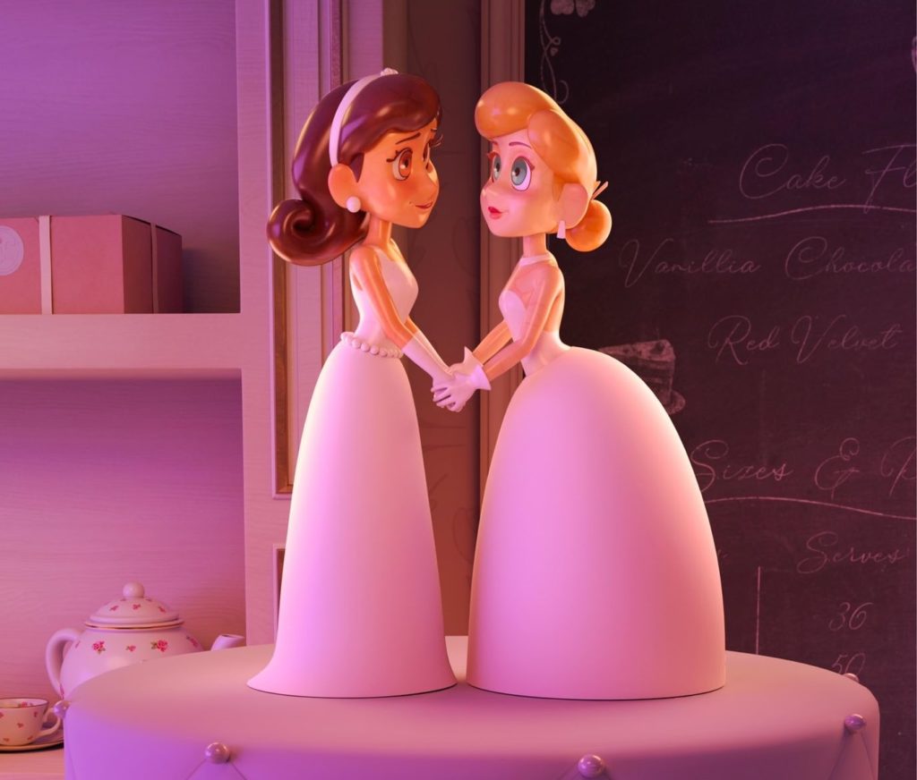 A photo still from Piece of Cake. It shows two cake toppers, both women in wedding dresses, holding hands and staring into each other's eyes.