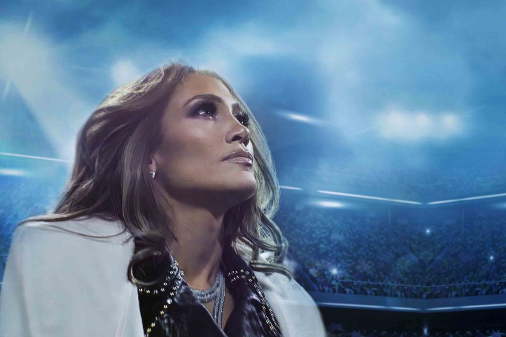 A close up photo of Jennifer Lopez, in a football stadium, looking up and just off right of the camera.