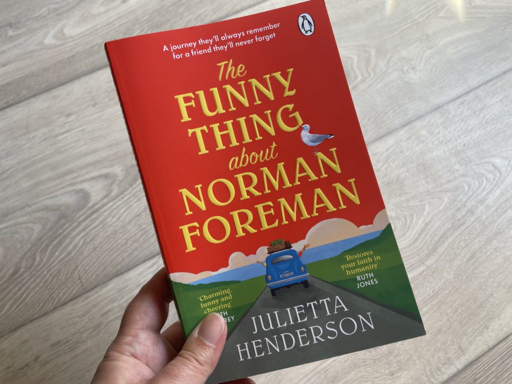 A close up photo of a hand holding the book, The Funny Thing About Norman Foreman.