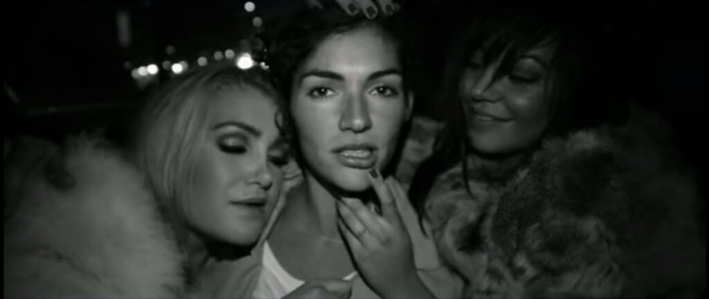 A photo still from the music video for Go by Freja Kirk. The image is black and white, and it depicts Freja Kirk in the centre, with a woman on either side of her, looking straight into the camera.