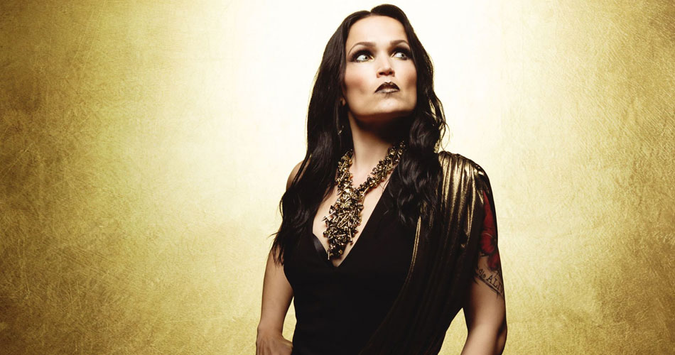 A promotional photo of Tarja Turunen. She is photographed from the waist up, looking off camera up to the right, against a striking yellow background.