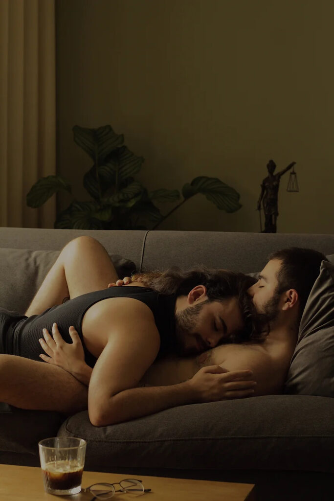 A photo by Jaime Prada. It depicts two people lying on a couch, holding each other in their arms.