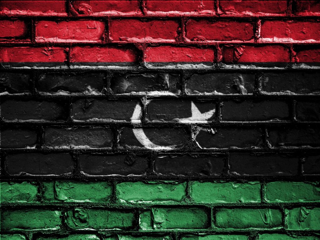 An image of the Libyan flag painted onto a wall of bricks.