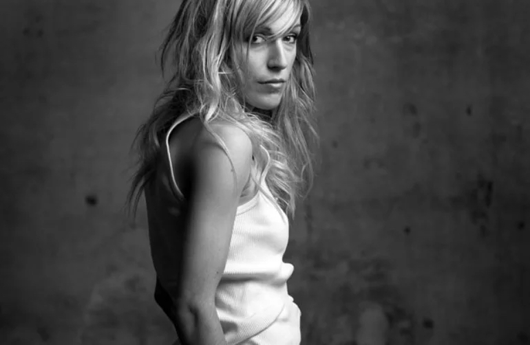 A black and white photo of Marta Roure. She is looking over her shoulder directly into the camera.