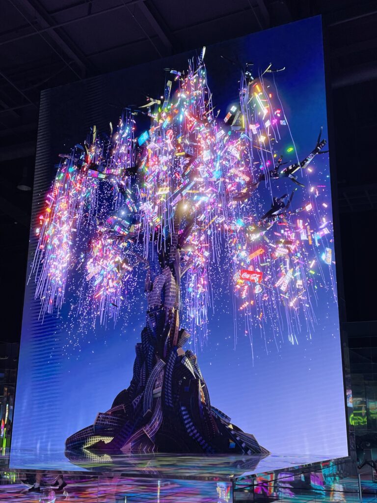 A photo of a digital artwork by Kim Yong Min at the Museum 1 in Busan, South Korea. It shows a single tree against a night sky, where the branches are made of light.